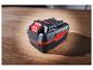 Batterie noire et rouge pour outils sur surface en bois.