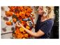 Femme utilisant un pistolet à colle chaude STEINEL pour fixer des soucis oranges à un mur.
