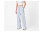 Femme en crop top blanc et pantalon de survêtement large bleu clair.