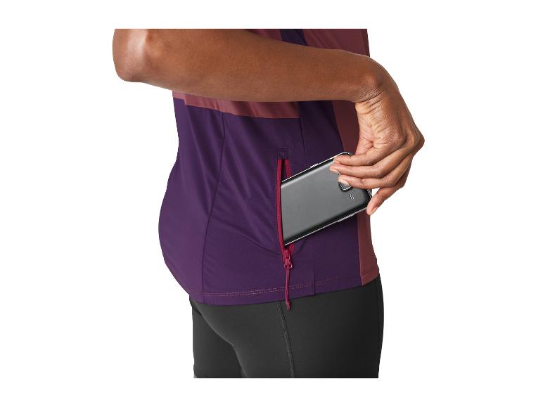 Femme en maillot de sport violet et noir, mettant un téléphone dans une poche latérale zippée.