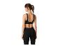 Femme en brassière de sport noire à motifs et leggings noirs, vue de dos.