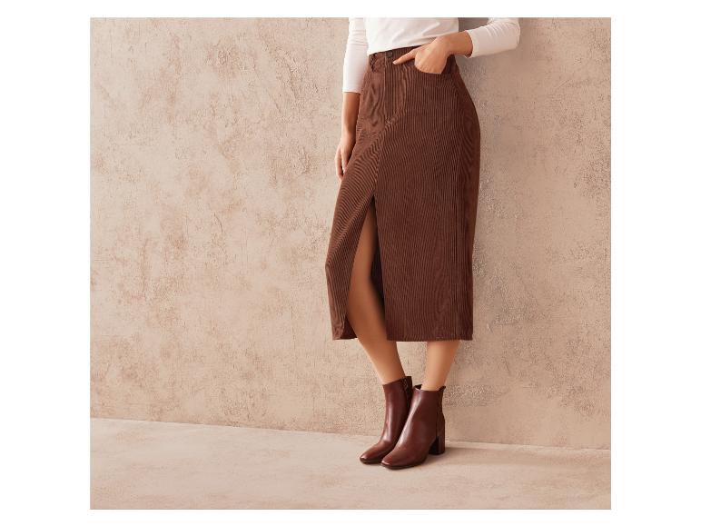 Une femme portant une jupe en velours côtelé marron et des bottines marrons.