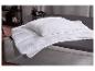 Couette et oreiller blancs sur un lit gris avec des draps foncés.