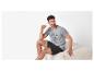 Homme en T-shirt gris et short noir assis sur un banc beige.