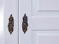 Deux portes blanches avec des poignées en laiton antique.