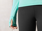 Une femme porte un haut à manches longues de couleur menthe et un legging noir.