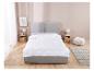 Couette et oreiller blancs sur un lit gris.