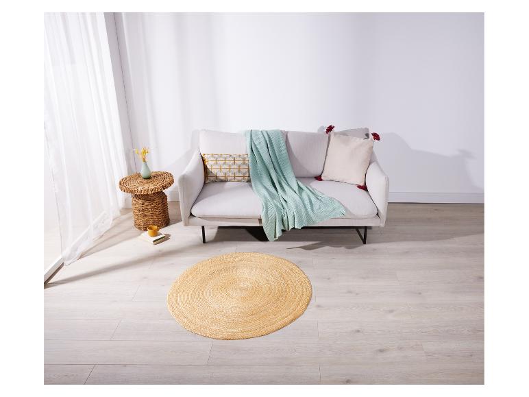 Un canapé beige avec une couverture menthe et un tapis rond en jute dans une pièce lumineuse.