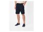 Homme portant un short bleu marine, un haut clair et des baskets bleues.