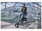 Une femme avec un pull vert, un jean bleu et des bottes noires avec un sac à main noir.
