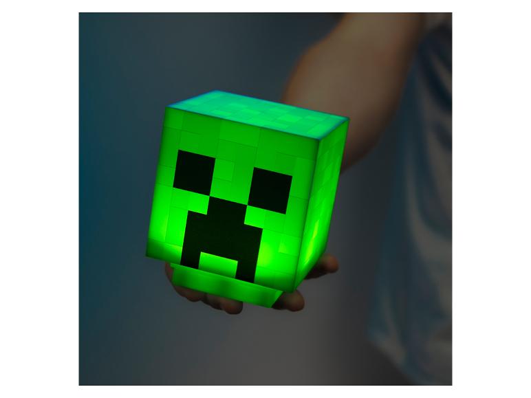 Boîte verte lumineuse avec visage de monstre, tenue dans la main