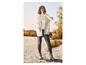Une femme portant un pull blanc, un legging noir et des bottes grises.