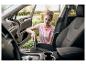 Femme passant l'aspirateur dans l'intérieur de la voiture avec un aspirateur à main.