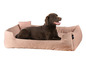 Un labrador brun dans un lit pour chien rose de la marque 'RÖHRSCHEIDER'.