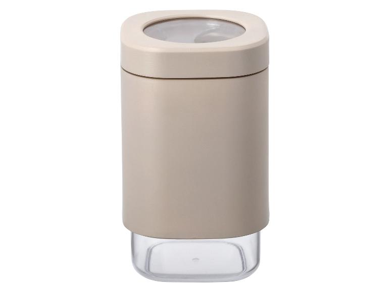 Un récipient à épices beige avec un couvercle transparent.