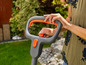Une femme utilise une tondeuse à gazon électrique dans le jardin.