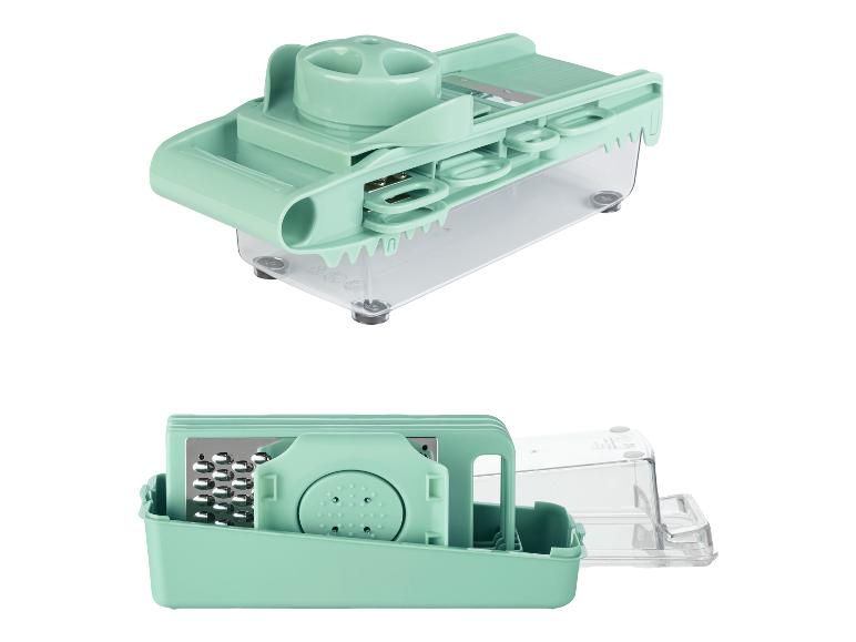 Une mandoline verte avec des lames interchangeables et une boîte de rangement.