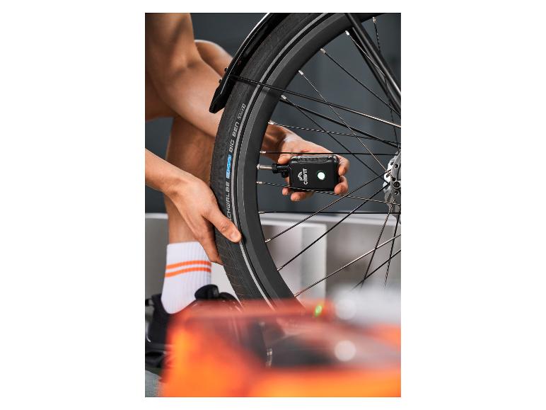 Personne gonfle un pneu de vélo avec une pompe à air portable.
