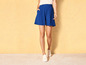 Une femme porte un short bleu et des baskets blanches.