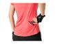 Femme en t-shirt de sport rose et gants, mettant une barre énergétique dans une poche.