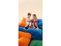 Deux enfants en survêtements et baskets sont assis sur des coussins colorés.