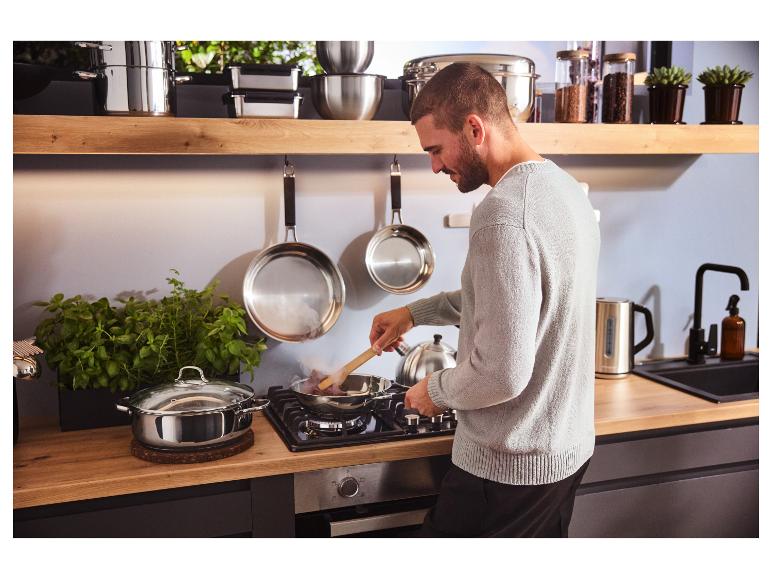 Un homme cuisine avec une poêle en acier inoxydable premium SILVERCREST® dans la cuisine.