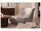 Fauteuil gris confortable dans un salon avec un meuble en bois foncé et une table basse.