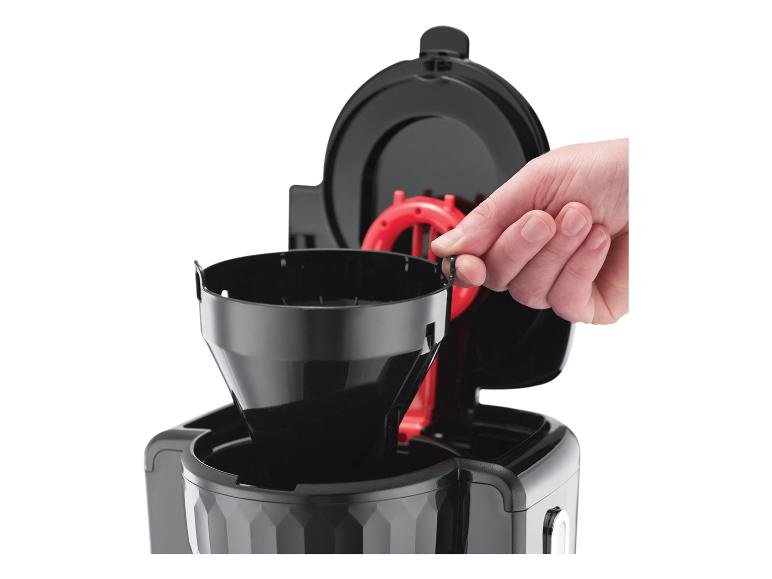 Une main insère un filtre à café noir dans une cafetière.