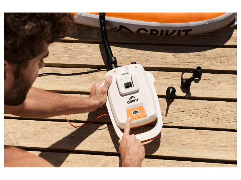 Homme gonfle une planche de SUP CRIVIT avec une pompe 20 V sur une terrasse en bois.