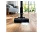 Aspirateur balai sans fil nettoyant un sol en bois, avec la mention 'POWER BRUSH'.