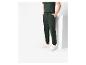 Un homme portant un pantalon de survêtement vert foncé et des baskets blanches.