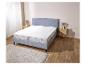 Un sommier gris avec un protège-matelas blanc.