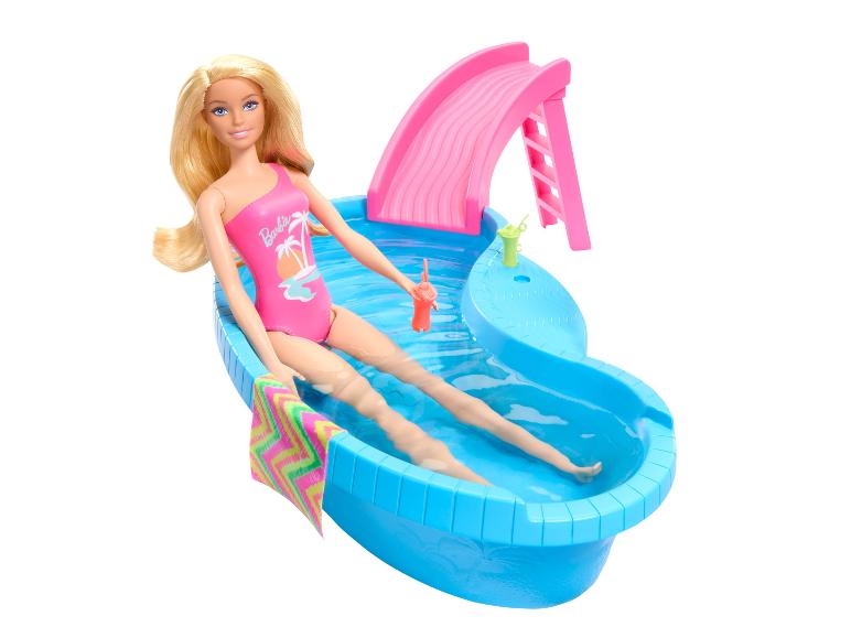 Poupée en maillot de bain rose se relaxant dans une piscine bleue avec toboggan.