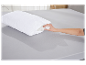 Main montrant le rembourrage d'un oreiller blanc matelassé sur un lit gris.