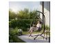 Femme lisant dans un fauteuil suspendu œuf avec coussins gris sur une terrasse de jardin.