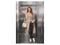 Femme en trench-coat beige, pantalon noir et baskets blanches avec un sac dans un ascenseur.
