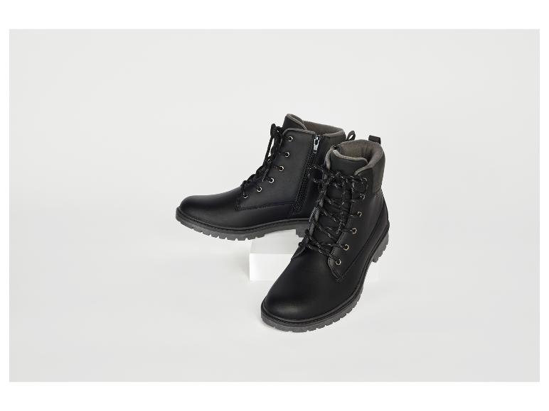 Deux bottes noires, l'une sur un support blanc, l'autre au sol.