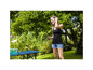 Une femme avec une raquette de ping-pong à côté d'une table de ping-pong dans le jardin.