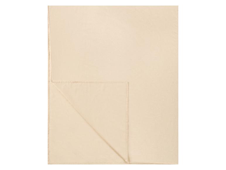 Couverture ou drap beige clair, plié avec un bord cousu.