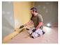 Homme peignant un mur, éclairé par la lampe de travail LIVARNO® «The Painter+».