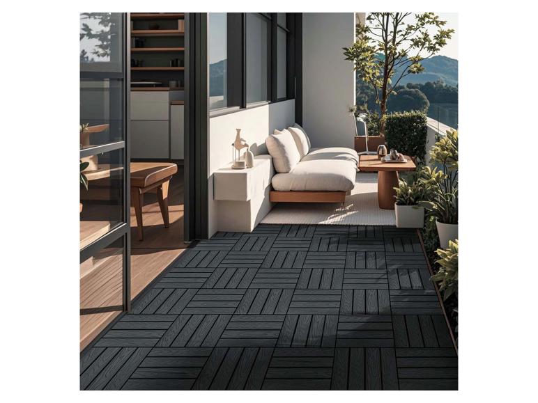 Dalles de terrasse foncées sur un balcon avec canapé et plantes.