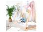 Un enfant lit un livre dans un lit Montessori en bois, décoré de tissus roses et gris.