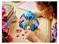 Une fille joue avec une figurine LEGO Stitch et de petites pièces sur une table en bois.