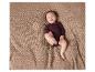Un bébé portant un body bleu foncé sur une couverture en tricot.