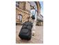 Voyageur tirant une valise et portant un sac à bandoulière près d'une gare.