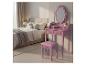 Coiffeuse rose avec miroir et tabouret dans une chambre à coucher.