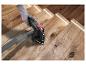 Main gantée utilise une ponceuse sur un escalier en bois avec des marches éclairées.
