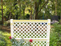 Une clôture en bois blanc avec un motif de treillis dans un jardin.