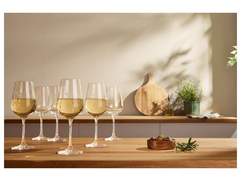 Verres de vin blanc sur une table en bois, avec des olives et des herbes.