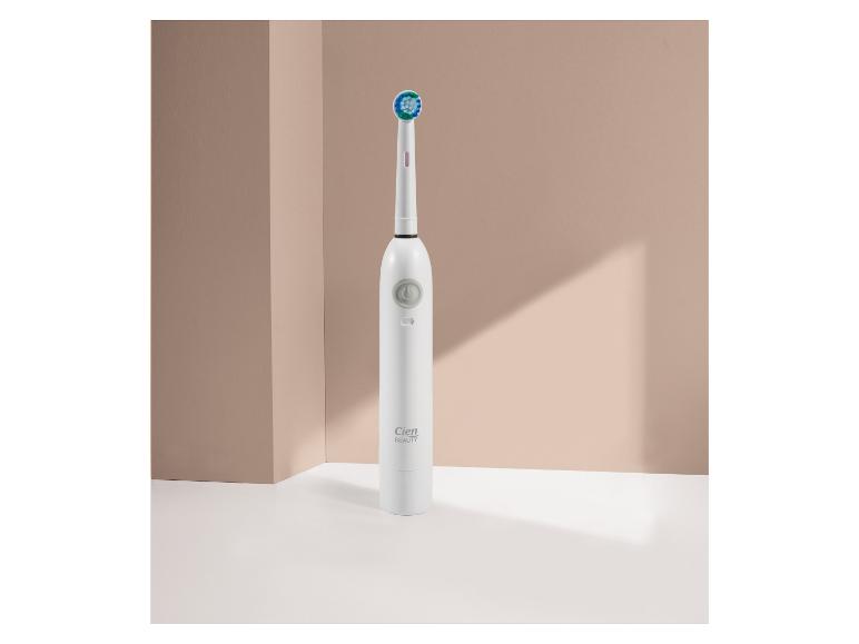 Brosse à dents électrique blanche Cien Beauty avec tête verte et bleue sur fond beige